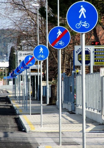 Alternarsi di cartelli di inizio pista e fine pista ciclabile davanti a passi carrai